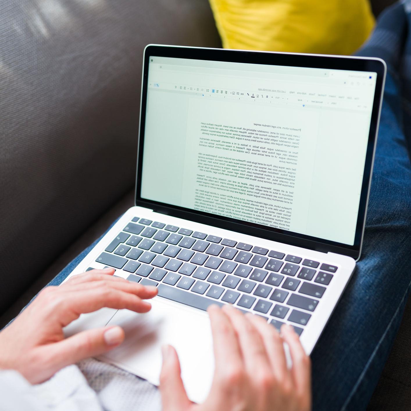 Hands typing an essay on a laptop computer